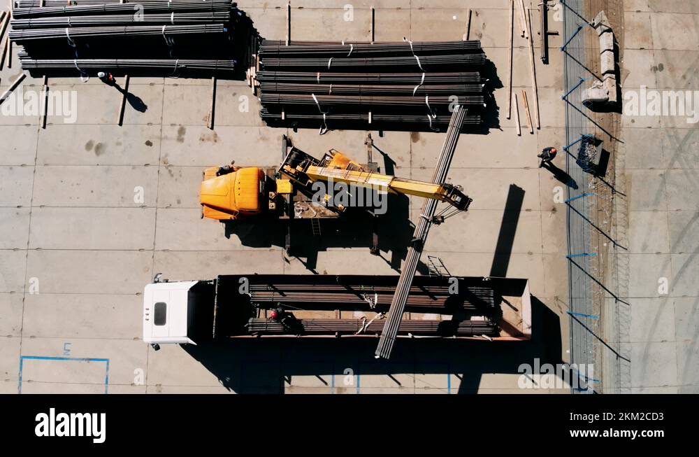 An industrial crane loads a section of Drilling pipes into a truck bed