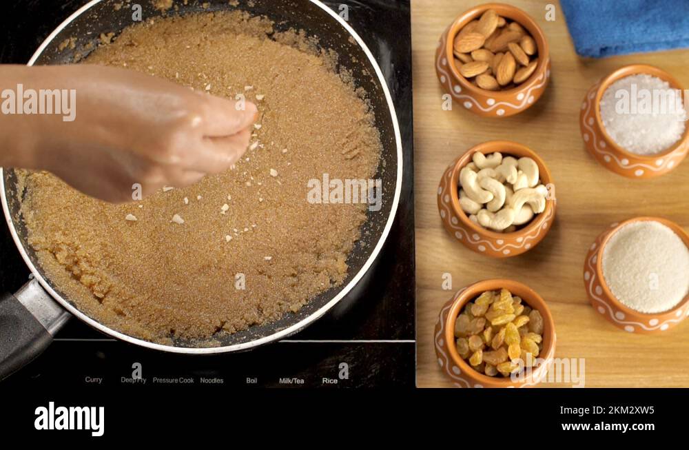 Grated dry fruits and raisins being dropped on top of freshly prepared