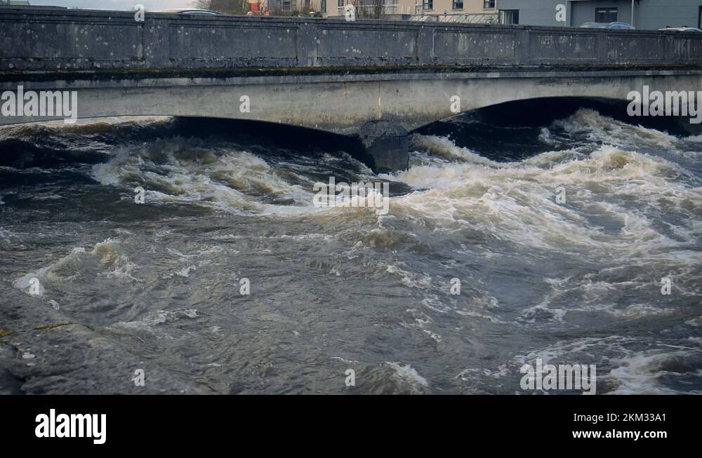 Rain swollen River Corrib rushing and churning under a bridge in Galway