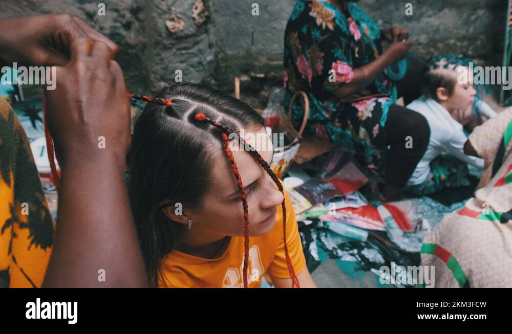 African Woman Weaving African Braids with Red Kanekalon Outdoor