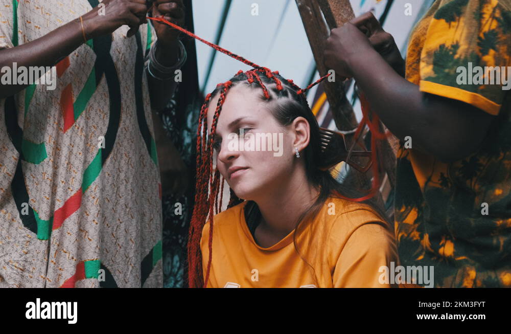 African Woman Weaving African Braids with Red Kanekalon Outdoor