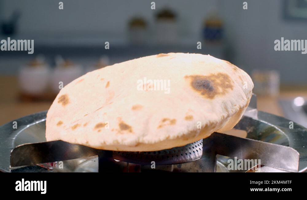 Indian cook making fresh chapatis on a gas stove using a tong cooking