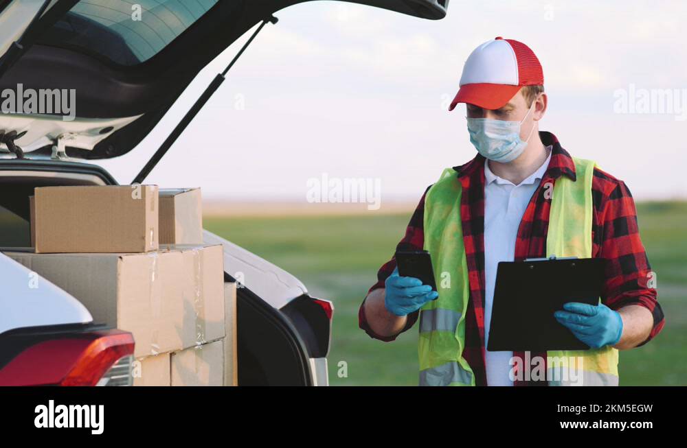 Young delivery man checking list. Delivery man in cap and documentation ...