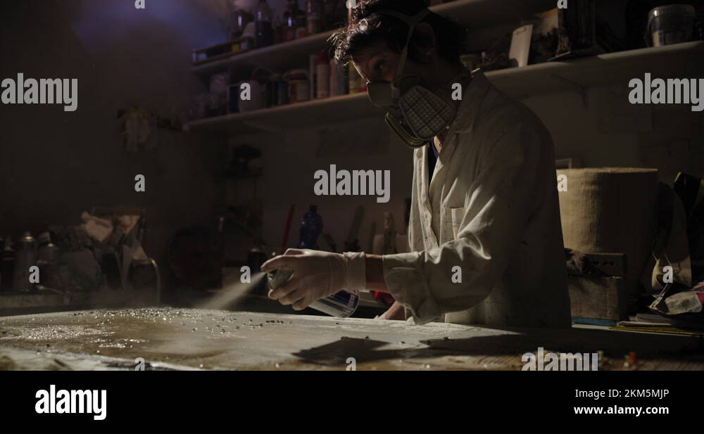 Female painter with respirator and gloves painting with oil colors on