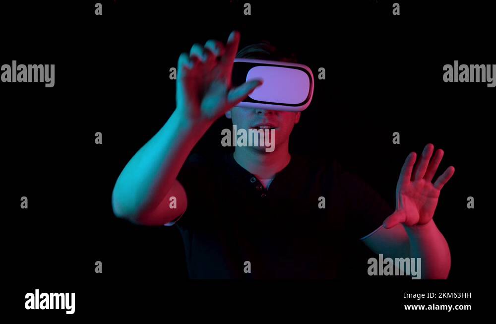 Young man in VR glasses. A man immersed in virtual reality makes ...