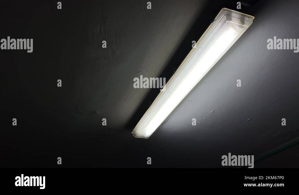 Broken flickering fluorescent lamp flashes on the ceiling of a dark
