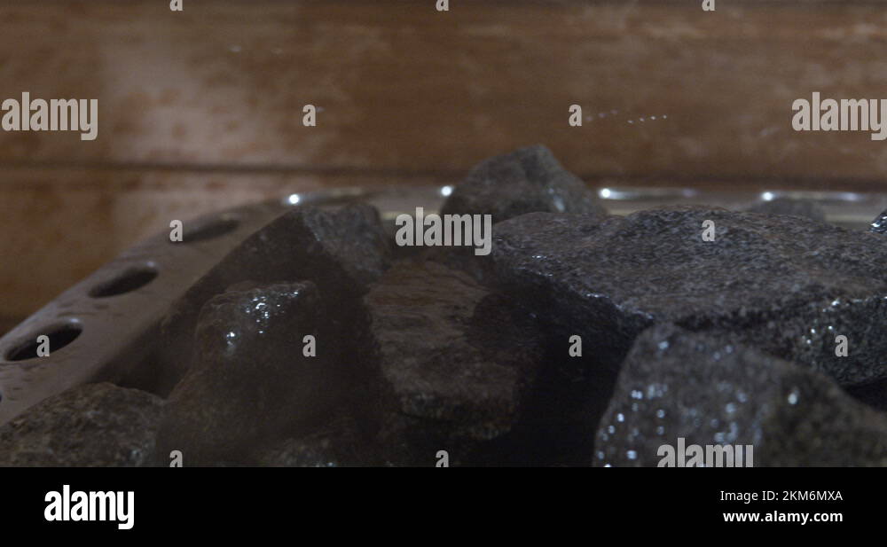 Pouring water on hot sauna rocks to generate steam inside the sauna