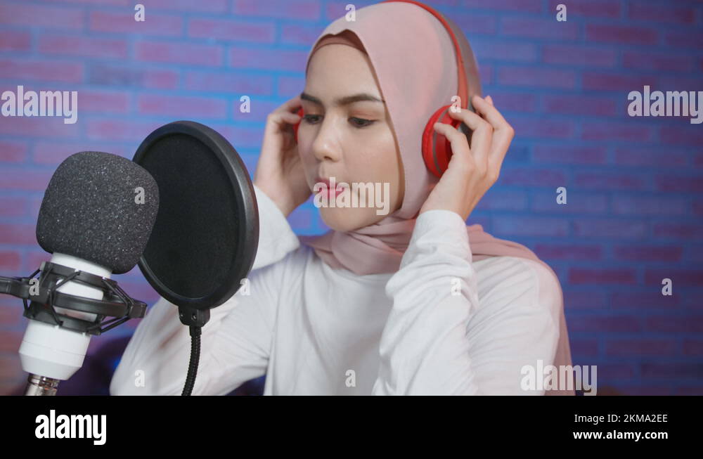 Young smiling muslim female singer wearing headphones with a microphone