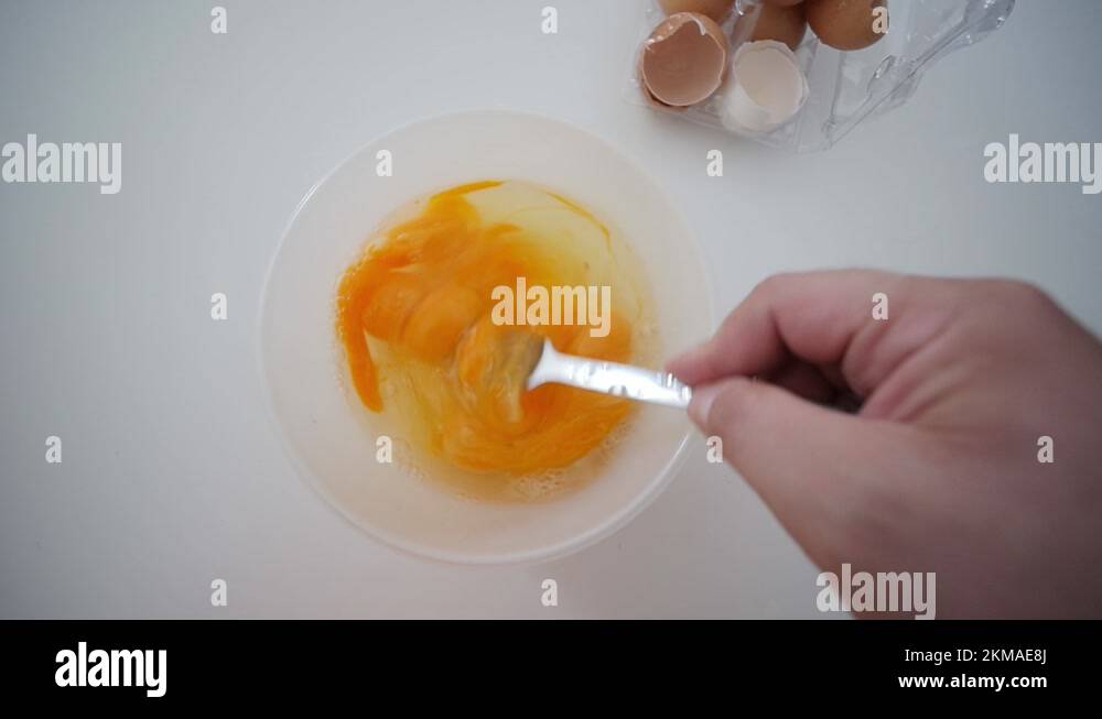 Whisking Egg Yolks With Fork In Bowl Top View With Broken Egg Shells In