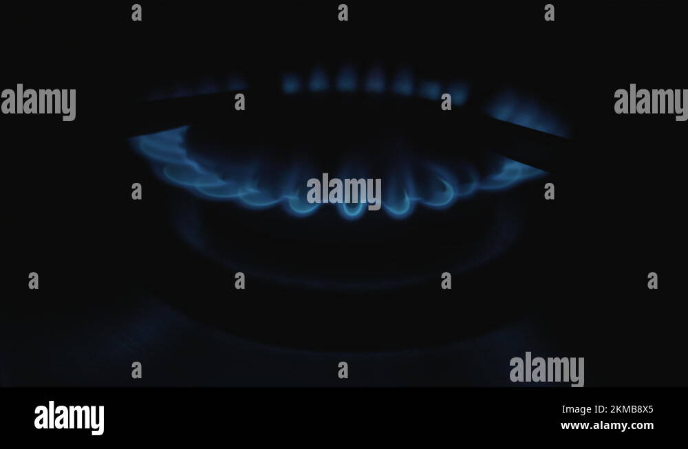 Moving flames of gas in gas cooker. Blue fire on stove in dark Stock