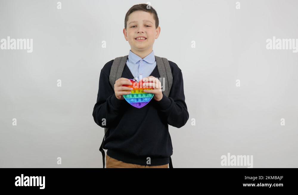 A joyful boy in school clothes with a backpack behind his back smiles ...
