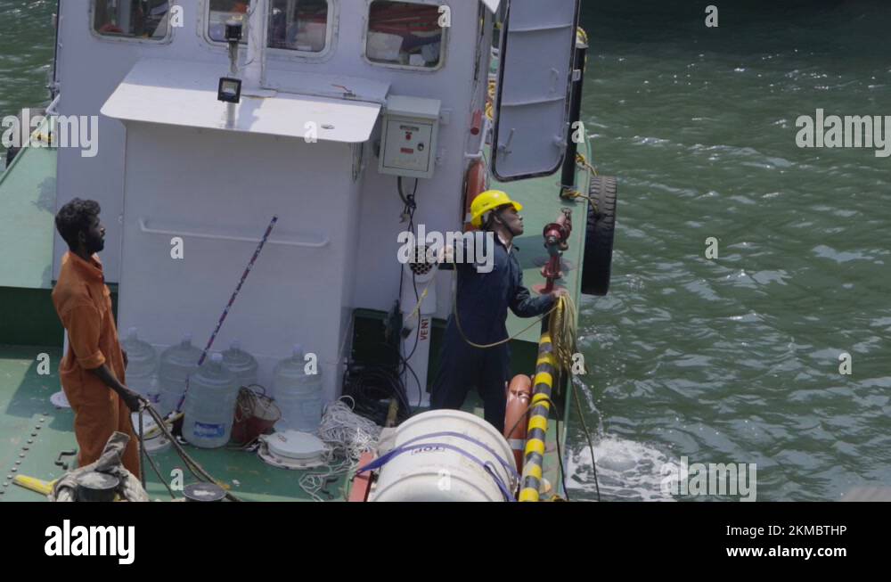 Dock Line Handling. Dockworker On Floating Boat Throws Mooring Line To