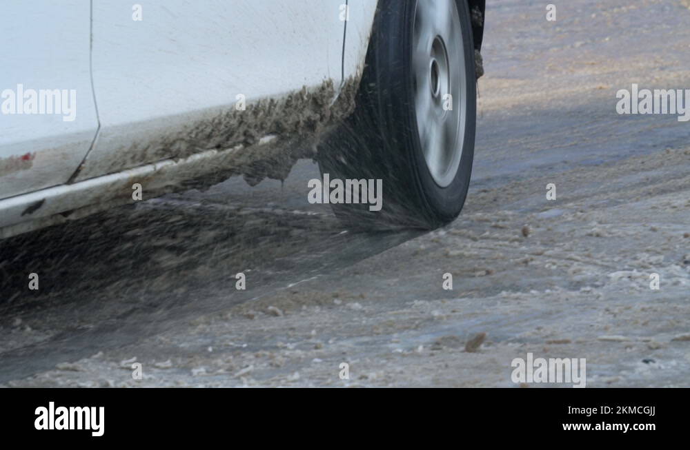 Close slow motion view of a car wheel slipping on the icy road surface