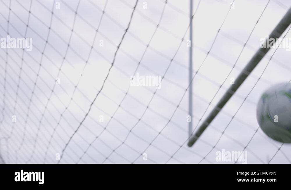 A soccer ball hits the back of the net under the football goal posts