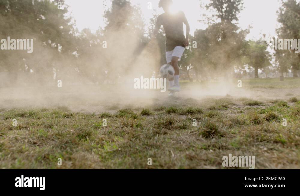 Boy kicks soccer ball in the air in dusty field Stock Video Footage Alamy