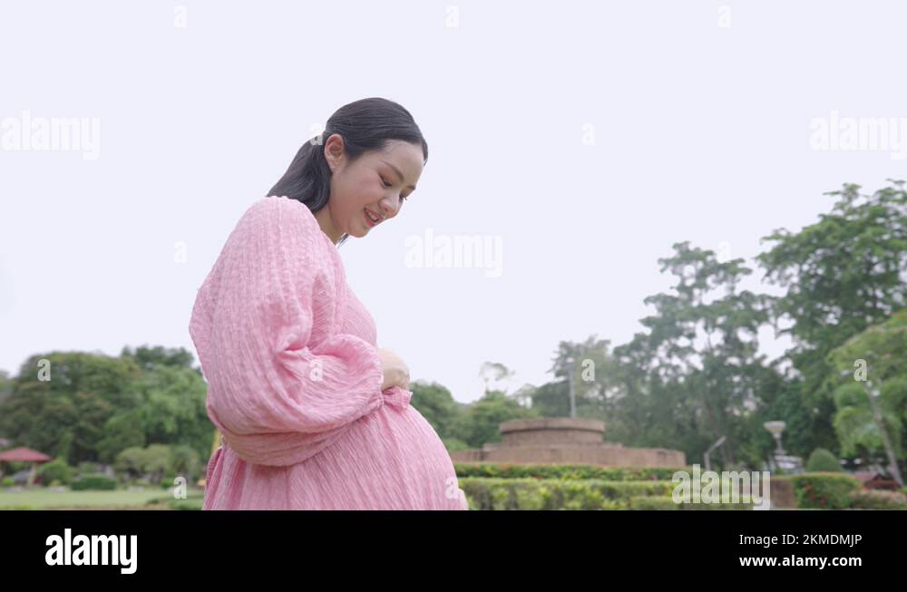 An excited a mother talks with pregnant belly while breathing fresh air