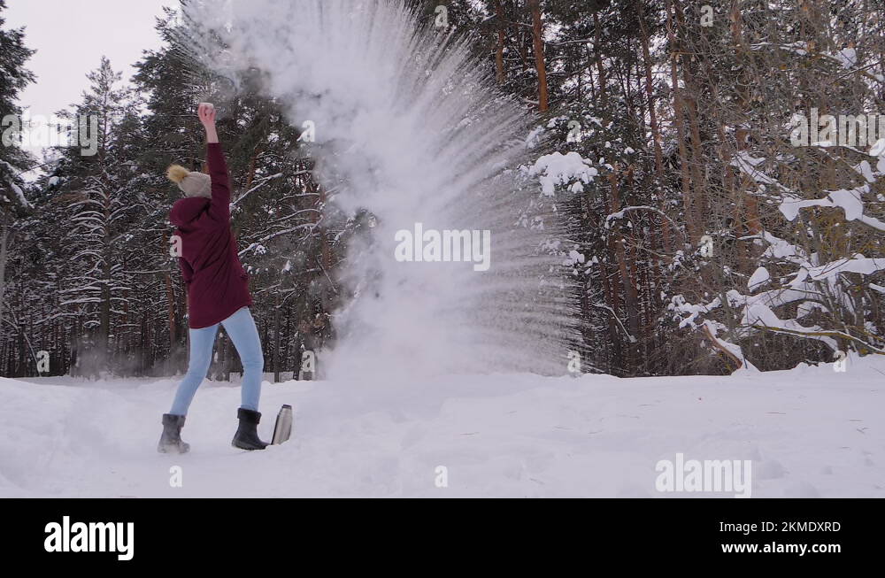 Woman throwing hot water in cold air, warm water turning to steam