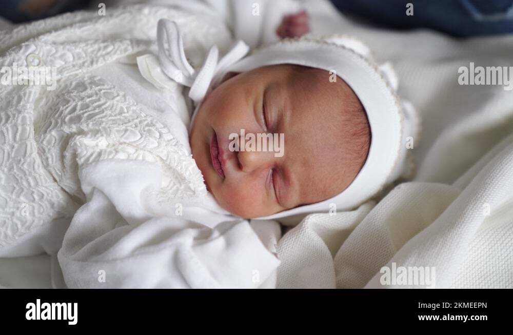Newborn baby sleeps in white clothes. attire for discharge from the