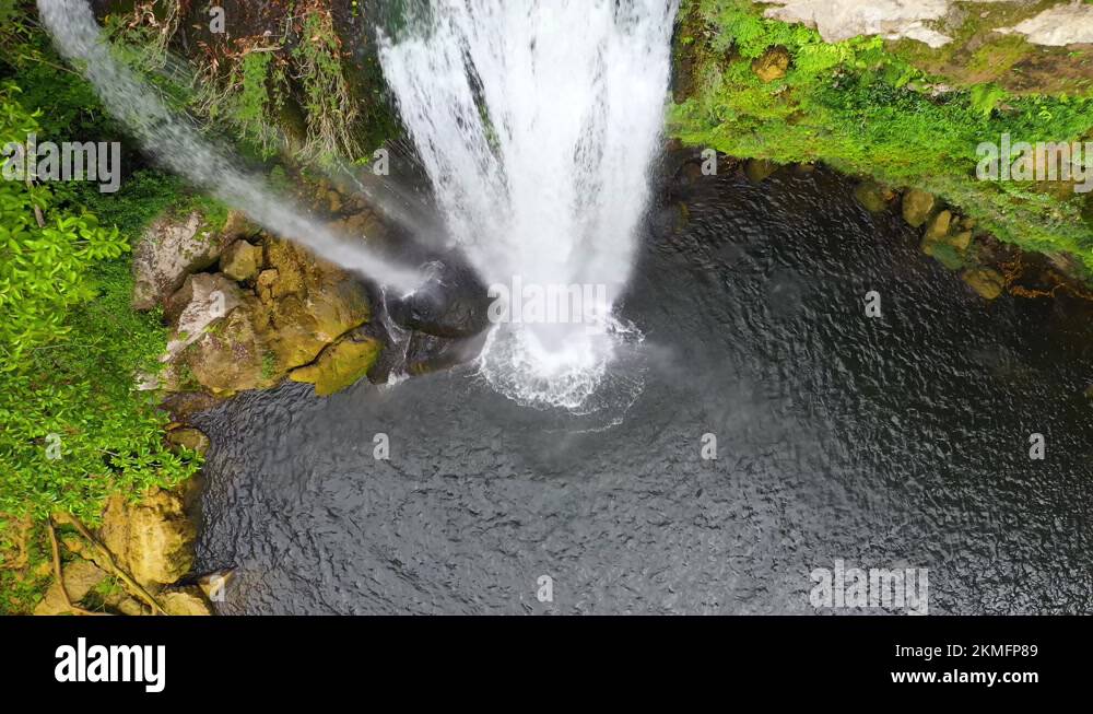 Aerial: top down view of waterfall overhang, river flowing over canyon