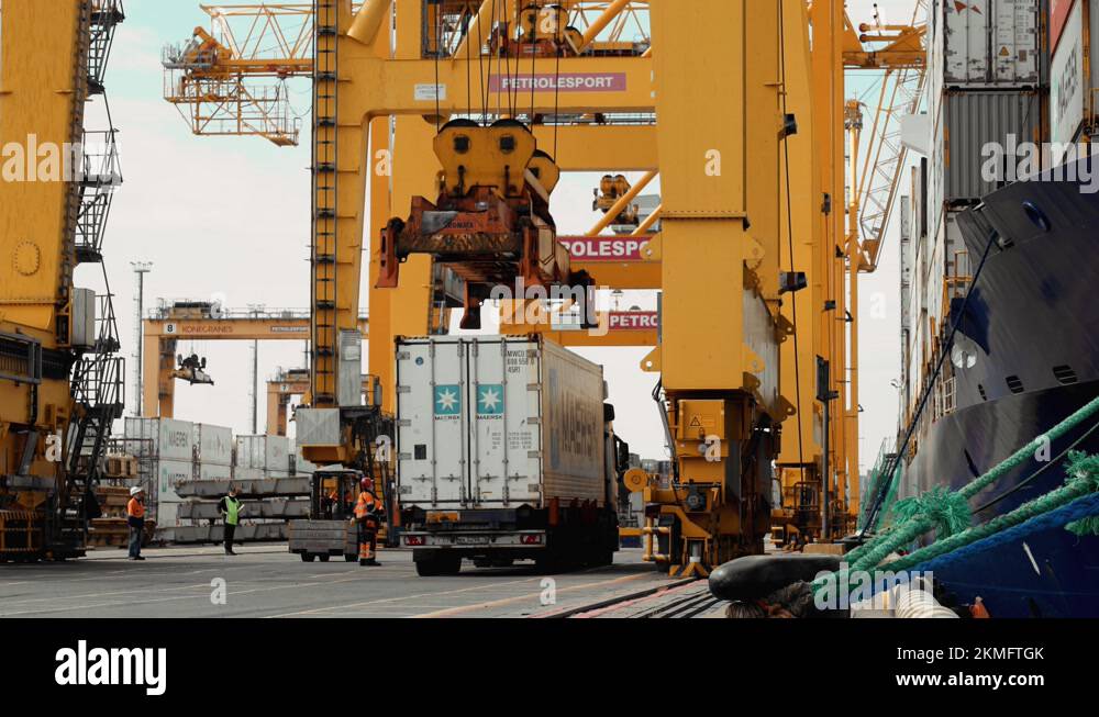 A huge crane lifts a container standing on a truck in the port Stock ...