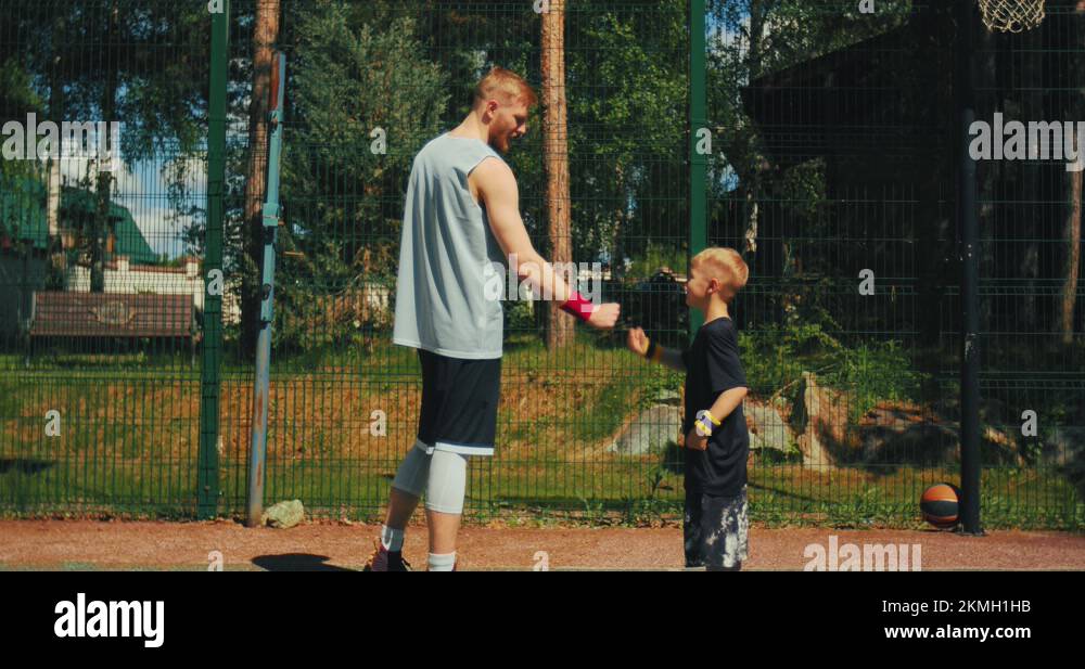 Basketball player give high five to son on basketball court. Dad, child