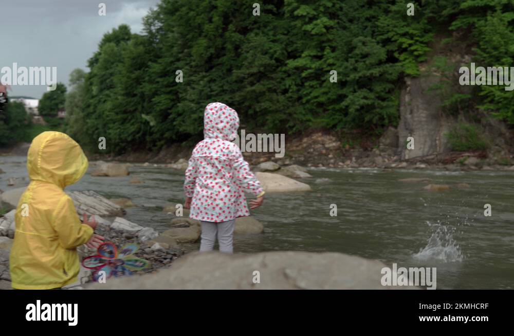 Little preschool children with mom on mountain river. Kids in raincoat