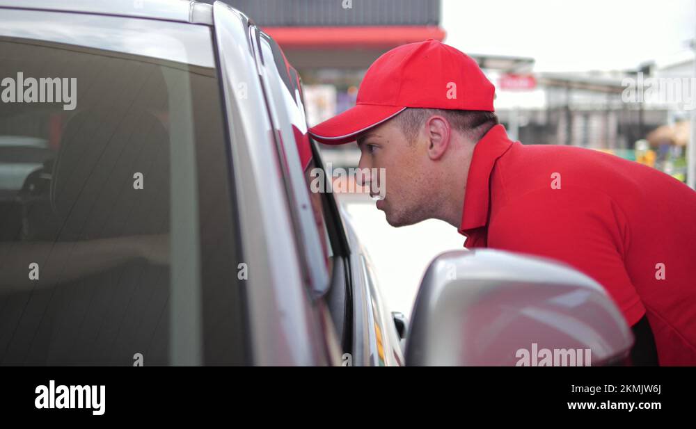 Man worker filling up fuel talking to a customer in car at gas station ...