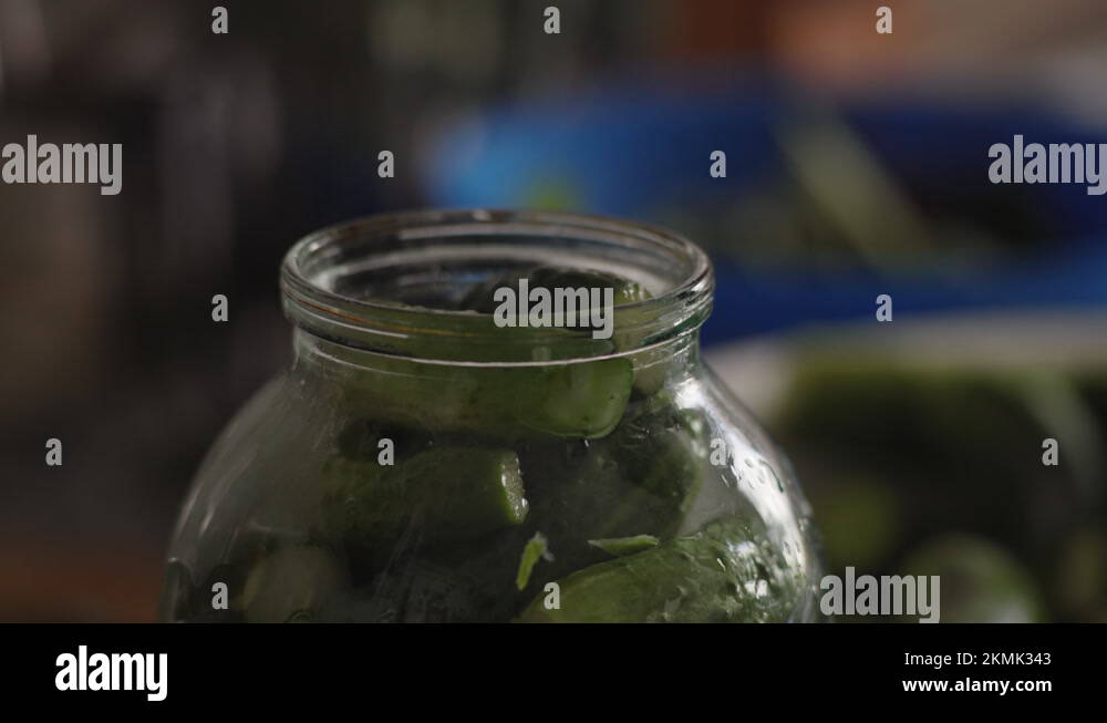 Closeup, Pouring Boiling Water into a Jar of Cucumbers for Marinade