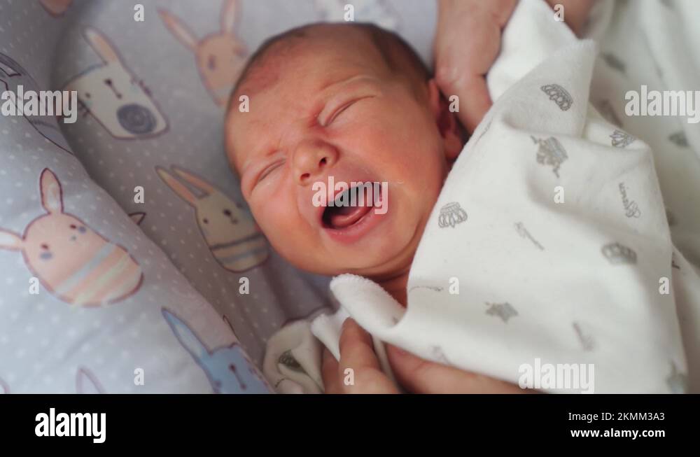 Mom's hands straighten the blanket at the sleeping in the crib of the