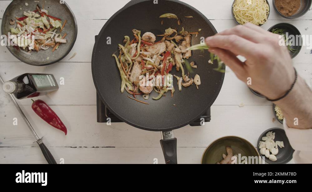 Cook in kitchen is cooking wok mixed roasting vegetables in the wok