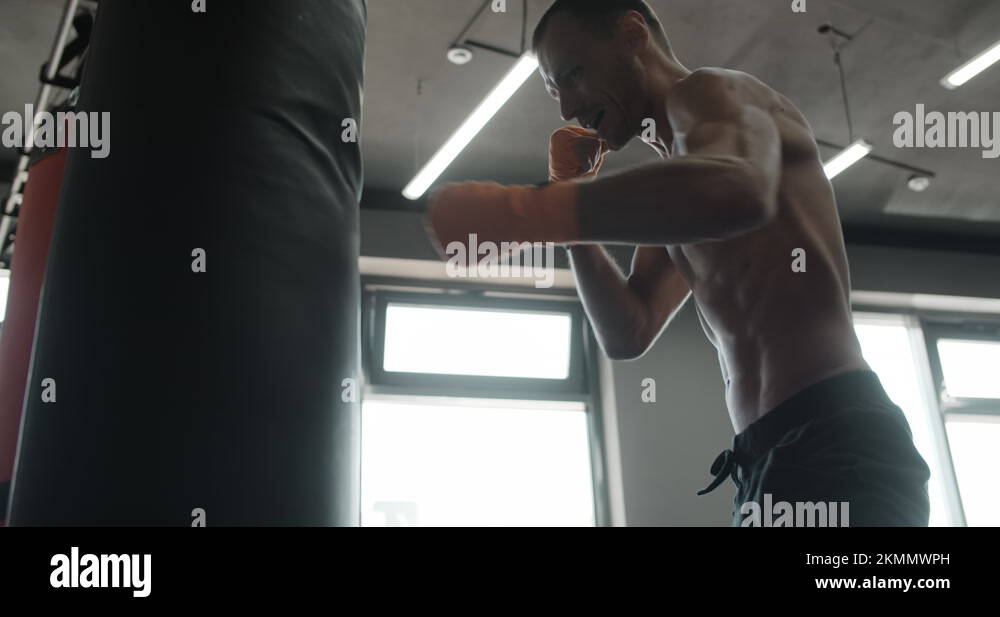 Mixed martial arts fighter punches and kicks boxer bag in slow motion, fighter Stock Video