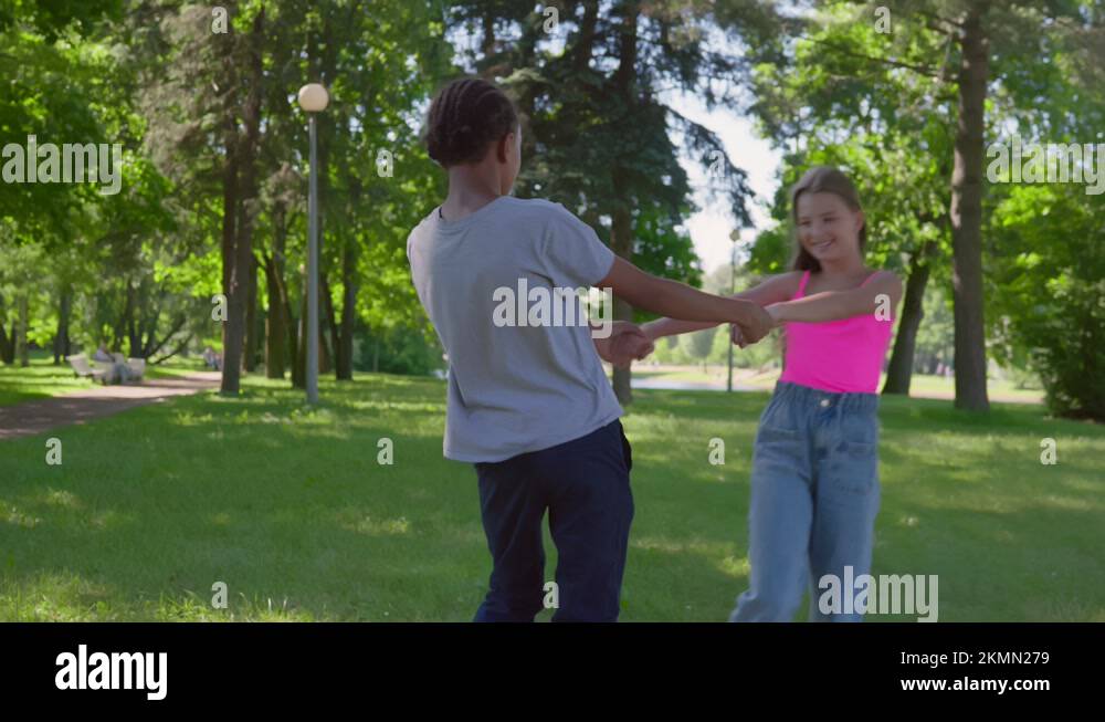 Teenage african boy and caucasian girl holding hands and dancing in ...