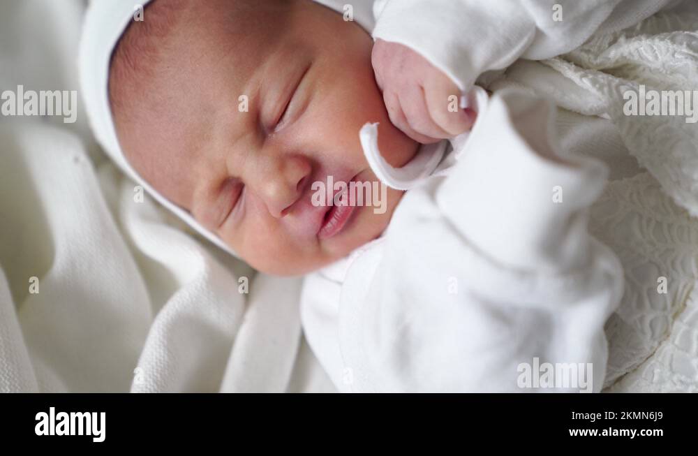 Newborn baby sleeps in white clothes. attire for discharge from the