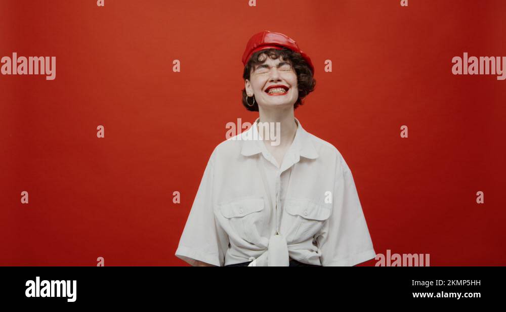 A woman with a short haircut in a red panama is crying