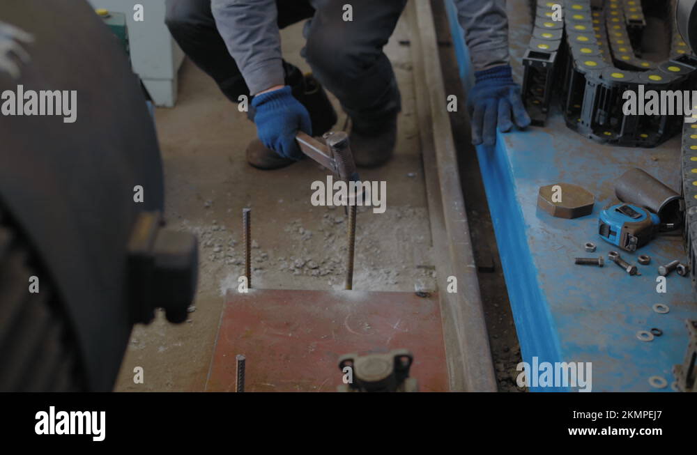 Closeup, Factory Worker Hammers Rebar into Hole Drilled in Concrete