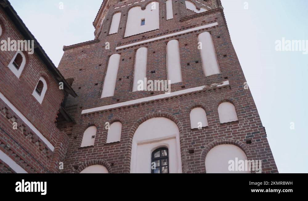 Bird nest in cell of brick wall of old medieval castle. Crow flies away