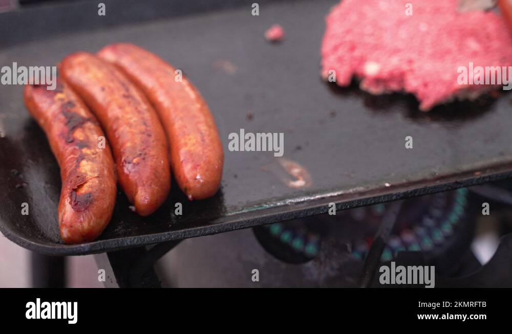 Sausage links meat grilling on cast iron skillet grill with hamburger beef Stock Video Footage