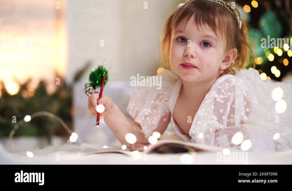 little girl writes a letter to Santa Claus under the Christmas tree