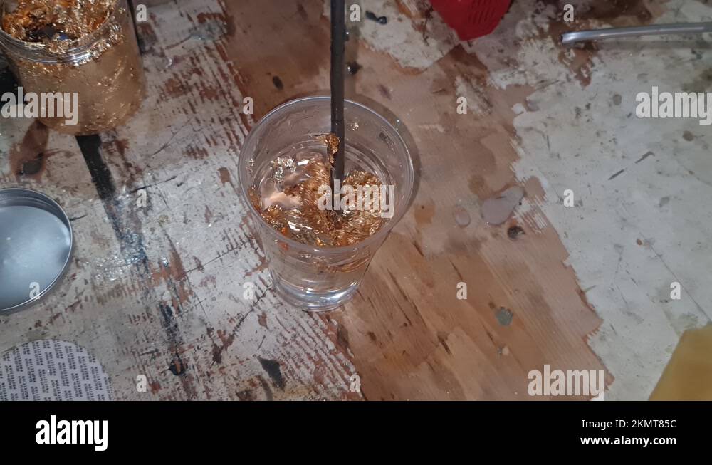 Mixing epoxy resin with golden leaves. Slow mixing with no bubbles on