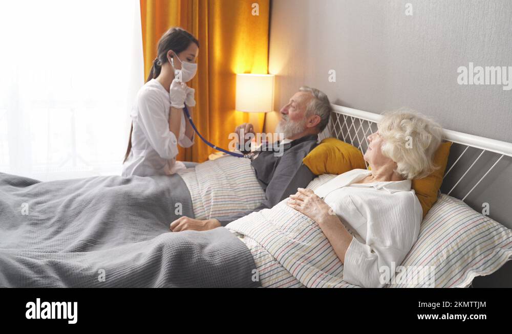 Female nurse checking sounds in heart and lungs of sick senior woman