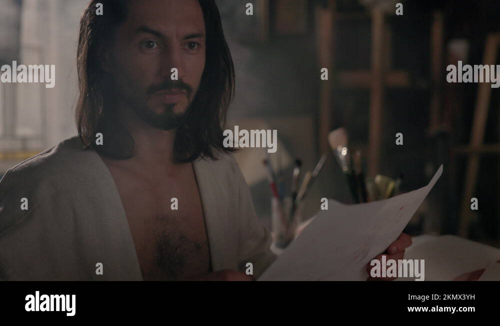 Young Artist In Art Studio. He Looks At His Drawing And Continues To