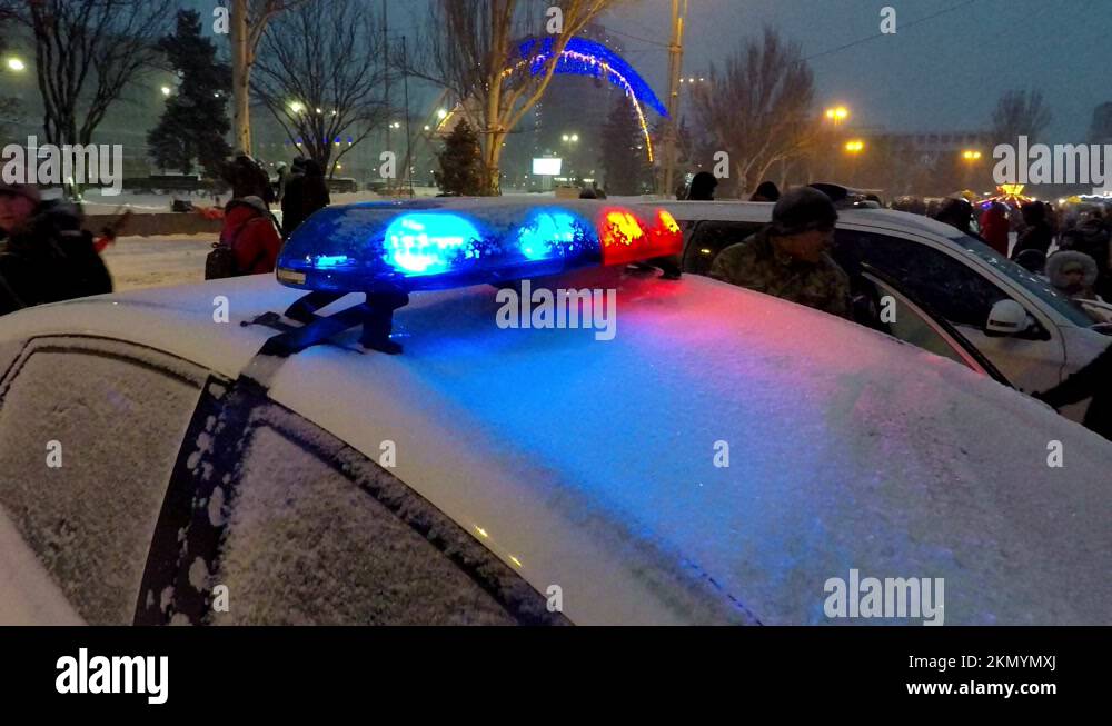 winter snowfall, people walk around police cars with flashing lights on