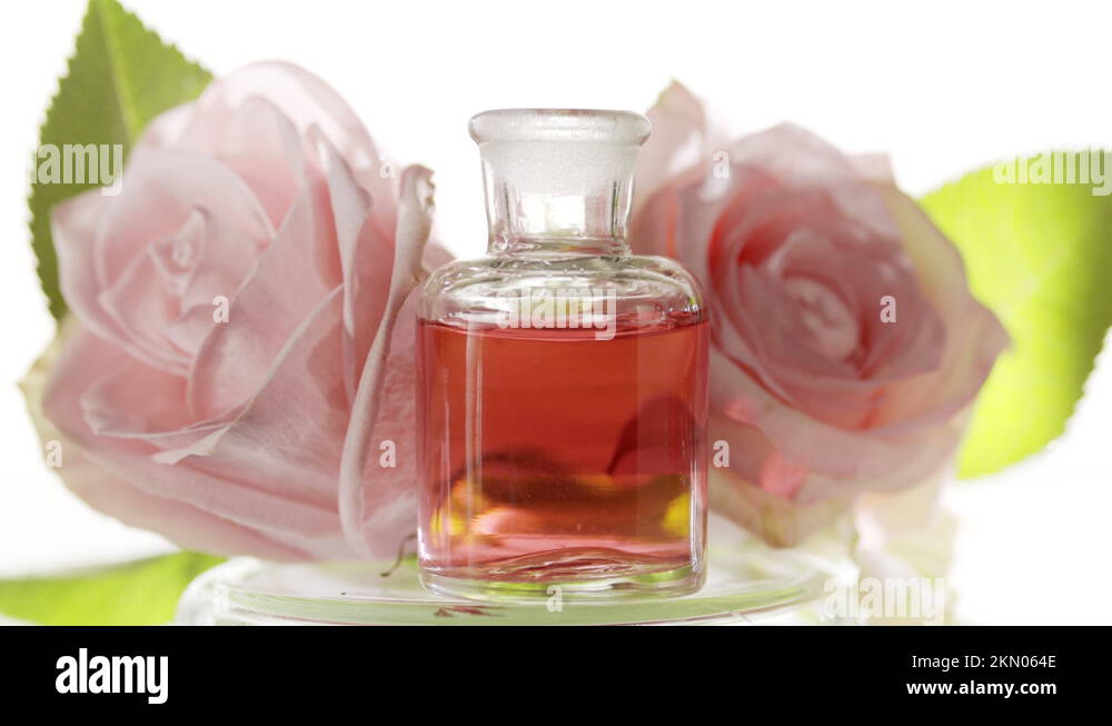 Drops of rose water fall into reagent bottle in front of roses Stock