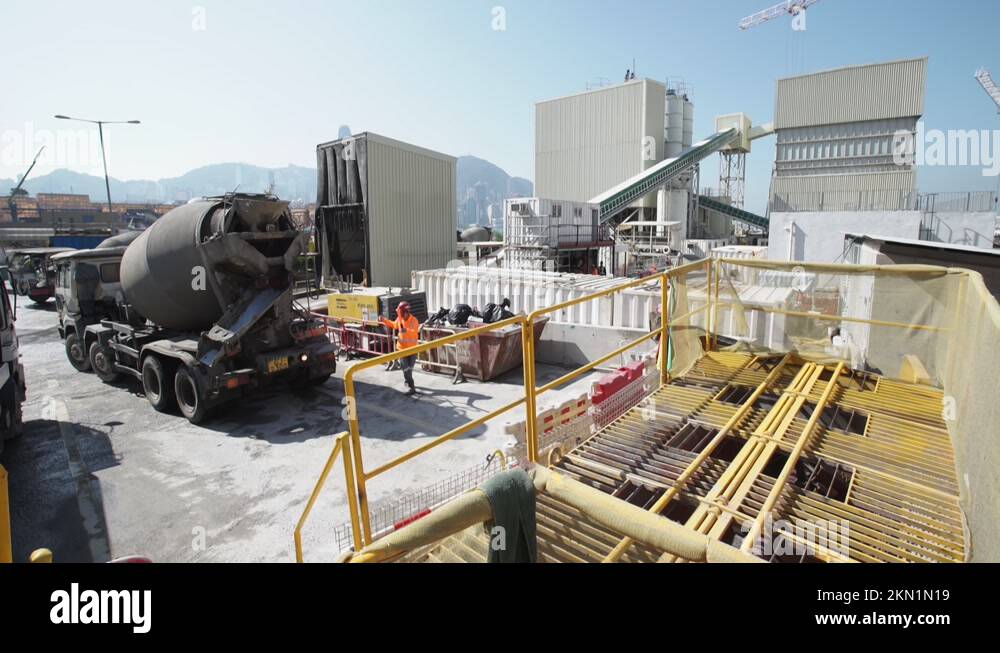 Truck Helper Directing A Concrete Mixer Truck Reversing At Cement