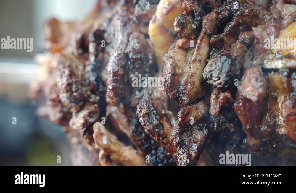 Juicy and spicy pork tenderloin roasting slowly on bbq grill hanging on