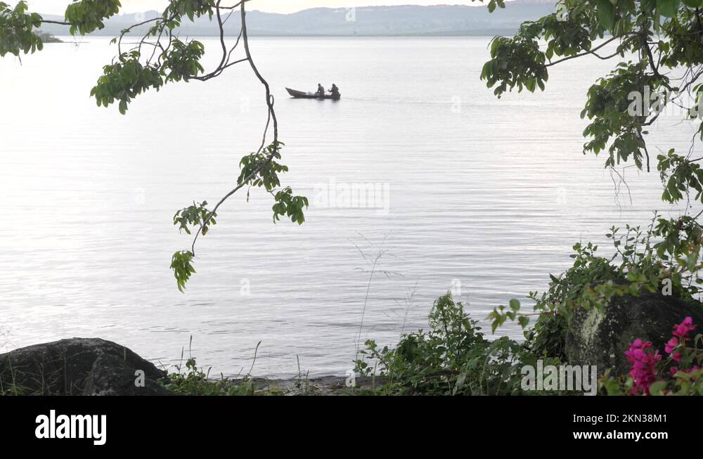 Two African men in the distance in a wooden canoe fishing on Lake