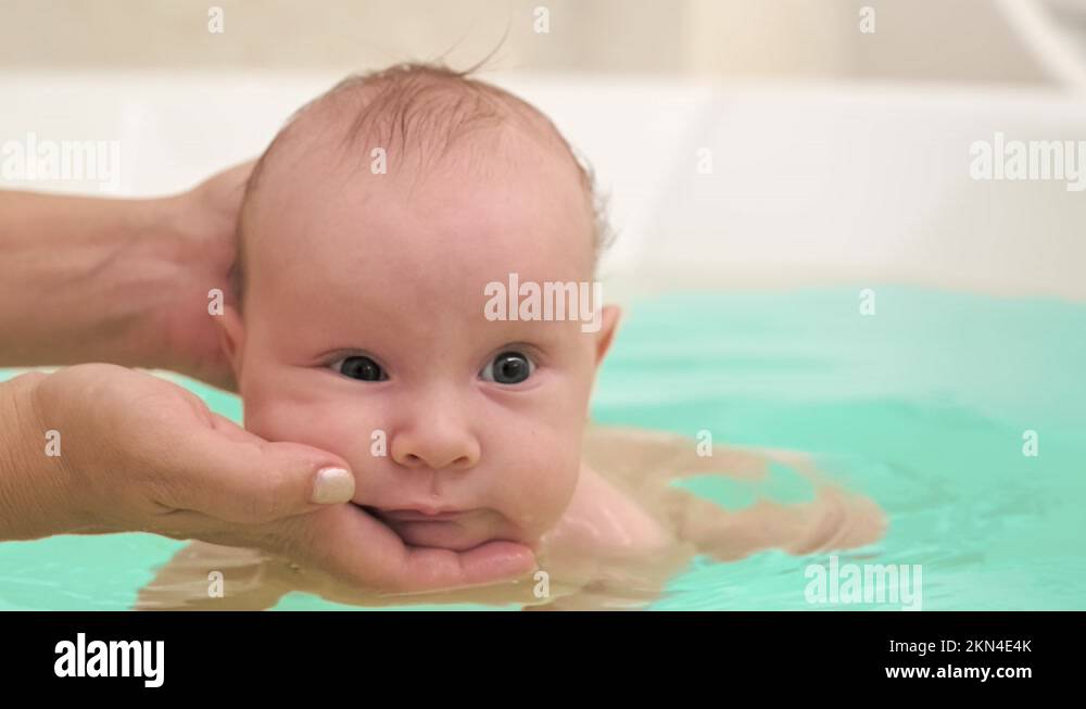 Mom teaches a newborn baby to swim and stay on the water. A twomonth
