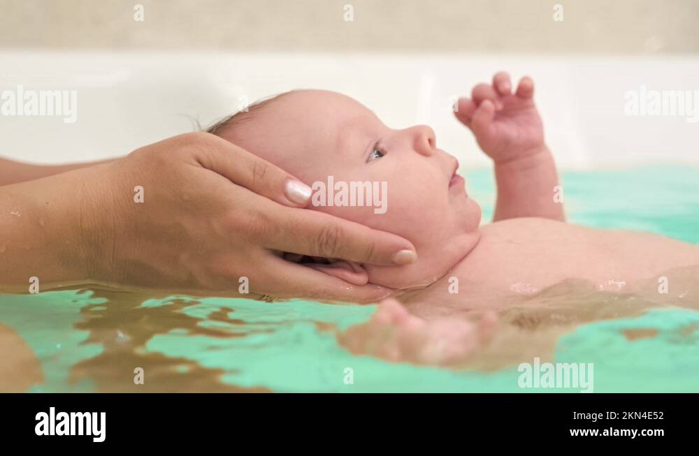 SLOW MOTION Mom teaches a newborn baby to swim and stay on the water