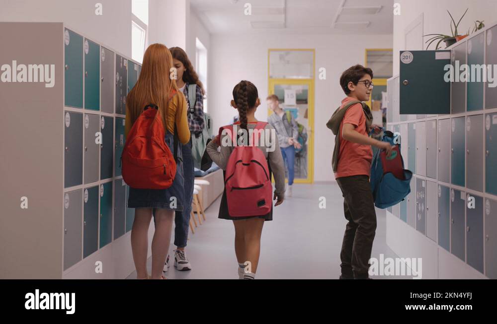 Children walk in school hallway, boy closes his locker. School hallway