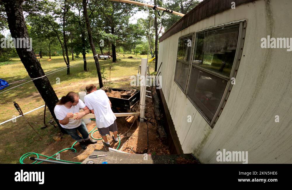 Men using levers to try pull plastic pipe from self excavated water